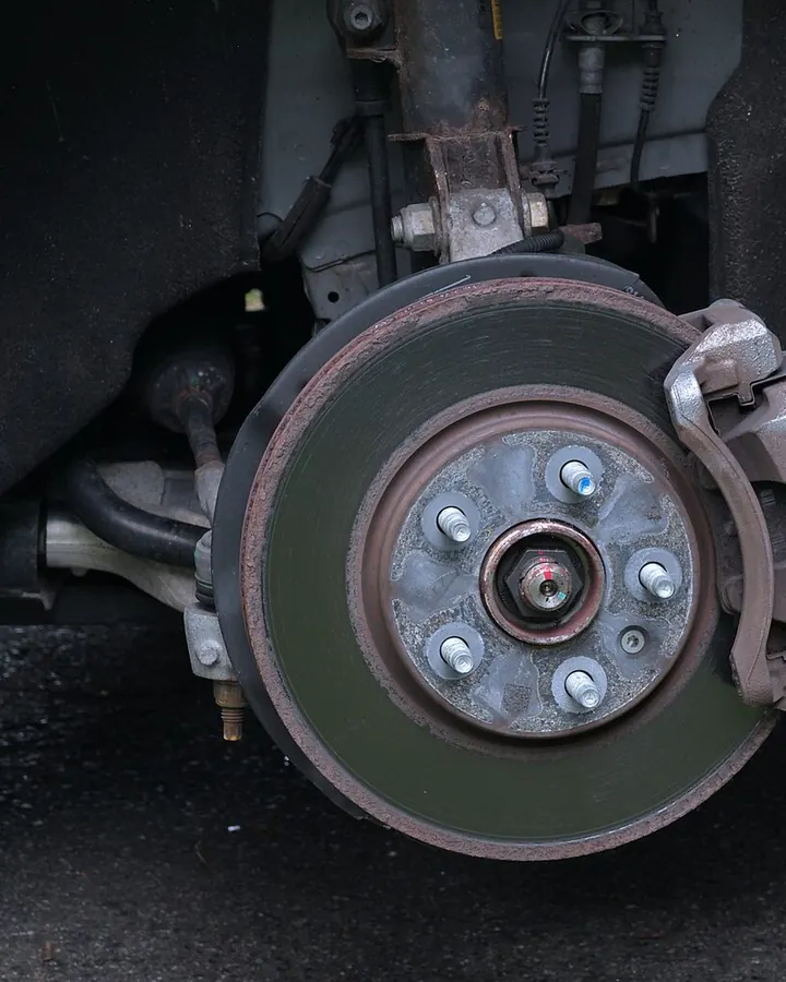 A brake disc and caliper on a car with the wheel off