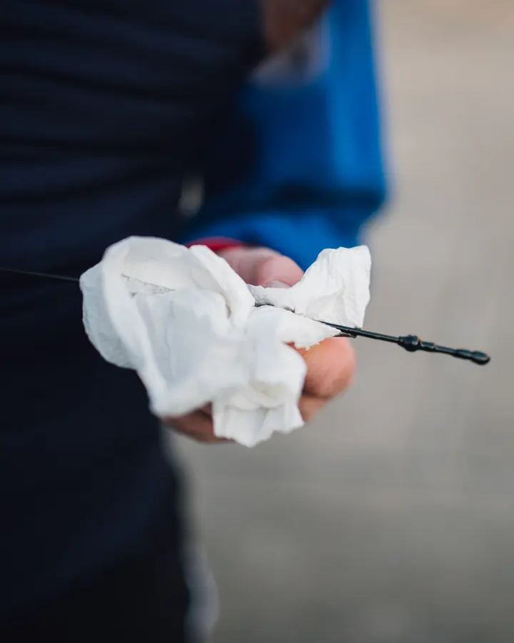 A hand holding an oil dipstick over a white cloth