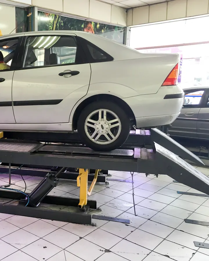 A silver car on an alignment rack with measuring targets on its wheels